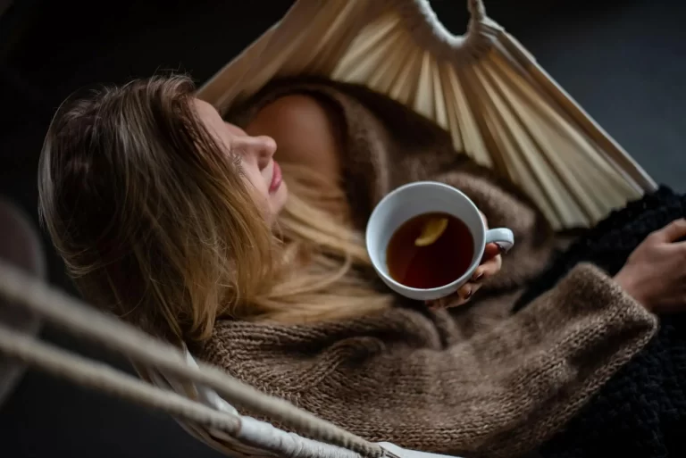 A person sitting in a hammock with a cup of tea