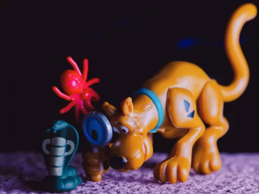 A plastic toy of scooby doo looking through a magnifying glass